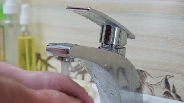 Turning on a faucet in a bathroom sink for washing hands