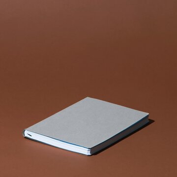 Used kraft cover composition notebook with a worn corner and blank label, featuring tactile paper textures for stationery mockups and copy space