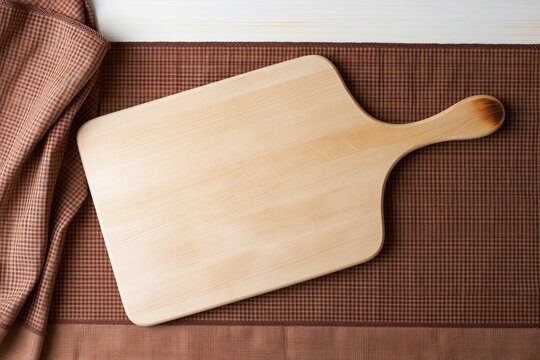 Rustic wooden chopping board with knife nicks and a scorch mark on a brown checkered cloth, providing a textured background and copy space for food styling