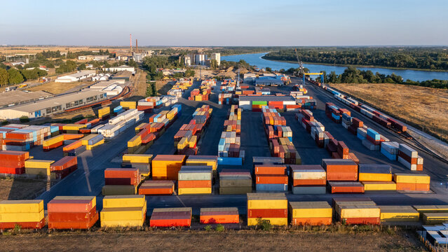 Aerial view of a shipping container terminal with rows of colorful containers, industrial facilities, and a river in Sremska Mitrovica, Vojvodina, Serbia.