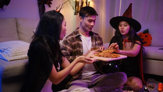 Young Asian friends sharing pizza together at a Halloween costume party.