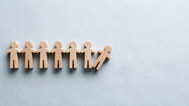 Wooden people figures in a row with one individual separated from the group on blue background