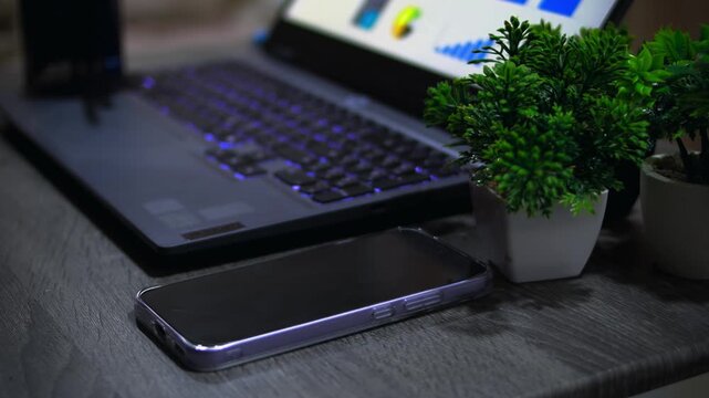 Businessman picking up smartphone from office desk after finishing work, representing end of workday and business completion.