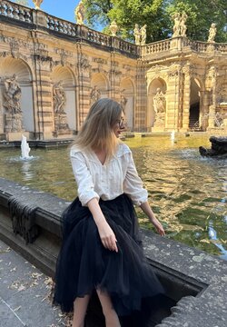 Elegant woman sitting by the fountain in courtyard at Zwinger Palace in Dresden, relaxing during summer vacation in Saxony, Germany 