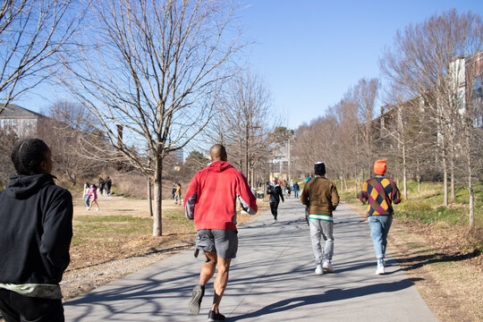 Atlanta, Georgia, United States - 18 January 2021: View of people jogging along the paved path of the Atlanta BeltLine on a sunny winter day with bare trees.