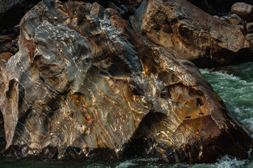 Swirling boulder bands beside a rushing river © ThamiShankar