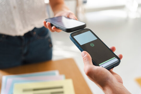 Two people perform a contactless transaction by tapping their smartphones together. This simple action demonstrates modern digital payments or data sharing between devices.