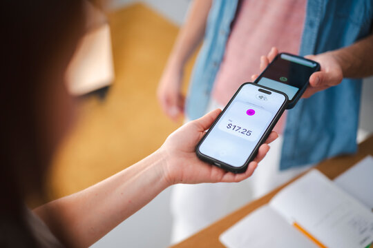 A customer makes a digital payment by tapping their smartphone against a merchant device for a transaction. This wireless process ensures a fast and easy checkout.