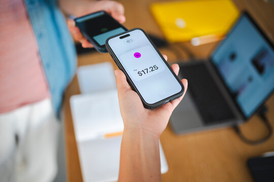 A person makes a contactless mobile payment by holding their smartphone over another device. This efficient digital transaction takes place in a modern office.