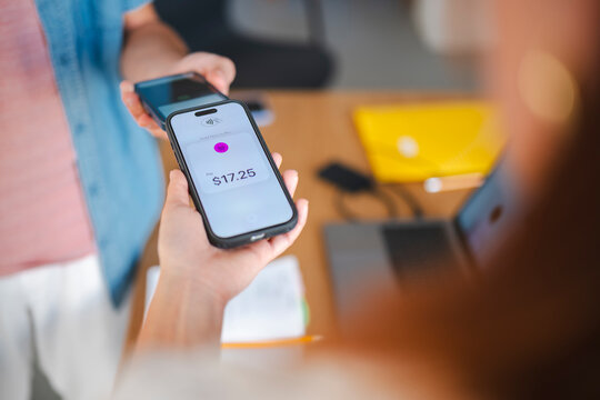 A customer completes a digital purchase by holding a smartphone near a payment terminal. The mobile screen indicates a transaction total of seventeen dollars and twenty-five cents.