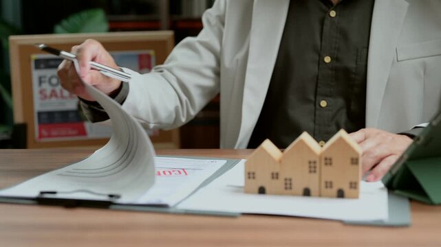 Real estate agent signs real estate contract paperwork, helping real estate agent client buy property.