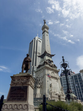 Indianapolis, Indiana, United States - 16 August 2026: View of the Soldiers and Sailors Monument with its limestone obelisk and bronze statues, set against a blue sky and modern skyscrapers.