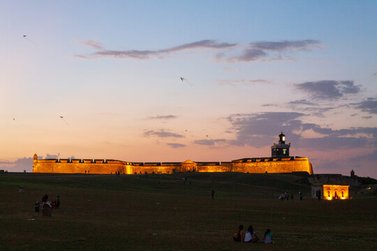 San Juan, San Juan, Puerto Rico - 22 March 2014: View of Castillo San Felipe del Morro illuminated at sunset with people flying kites on the lawn.