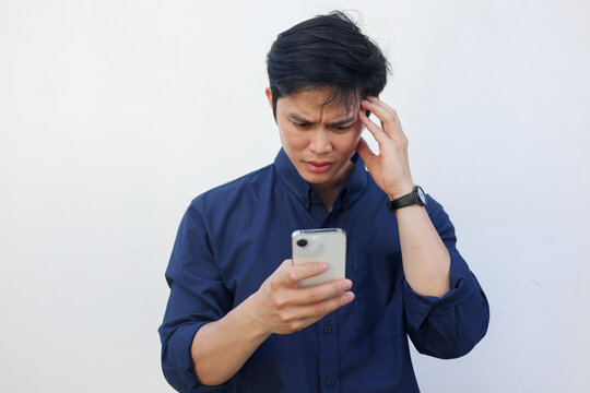 close up young asian man with stress emotion on face with during hold smartphone to reading about bad comment on social media application or read news and rumor in home for people lifestyle concept