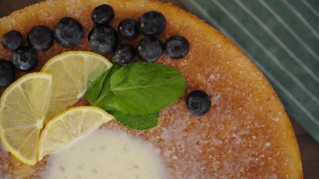 Hand presenting finished lemon blueberry cake in cozy kitchen