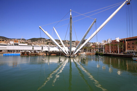 Genova, Italy - 19 July 2019: View of the Bigo panoramic lift and the Biosphere at the Porto Antico di Genova, with the historic city skyline and blue sky in the background.
