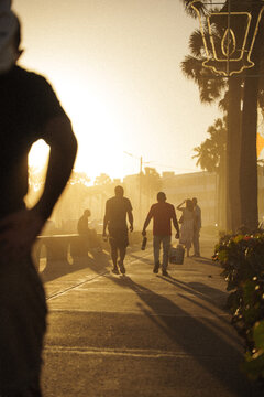 Santo Domingo, Dominican Republic - 19 January 2026: View of people walking along the Avenida Malecon promenade at sunset with warm golden light and palm trees.