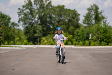 Naklejka premium Child first bike. Kid riding bike in a helmet. Child with a childs bike and in protective helmet. Articles on safety and summer activity. Happy kid boy having fun in summer park with a bicycle.