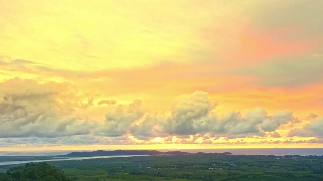  Aerial view of  A serene valley lies beneath a golden sky as soft fog flows like a river. The rising sun casts radiant beams that turn every cloud into a brushstroke of living color.