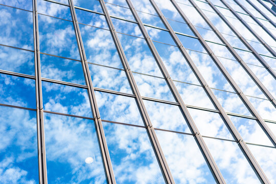 Low angle view of modern glass office building facade reflecting cloudy sky in Fukuoka, Japan