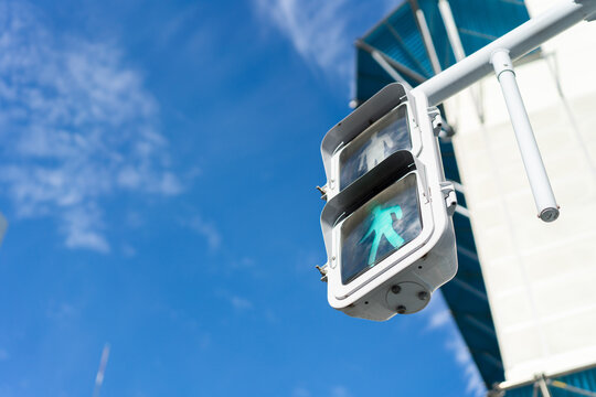 Low angle close-up of pedestrian traffic signal showing green light with copy space against blue sky in Japan