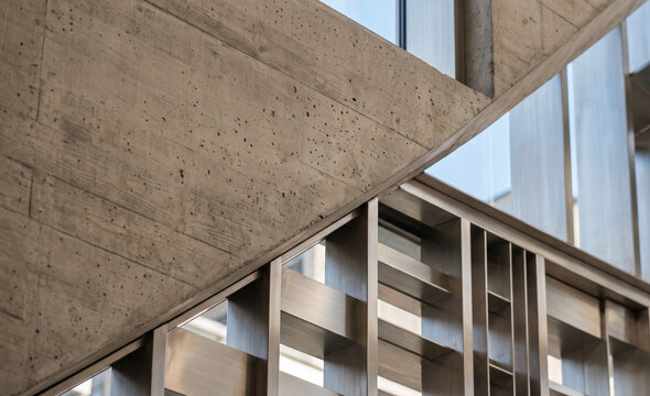 Abstract architectural detail of raw concrete intersecting with a modern metallic grid facade.