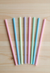 Fototapeta premium Plastic straw waste and environmental impact, colorful drinking straws on a wooden background, single-use plastic pollution