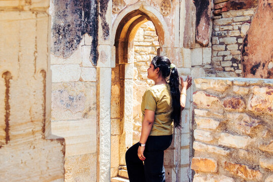side view of young modern woman in jeans looking inside fort of chittorgarh