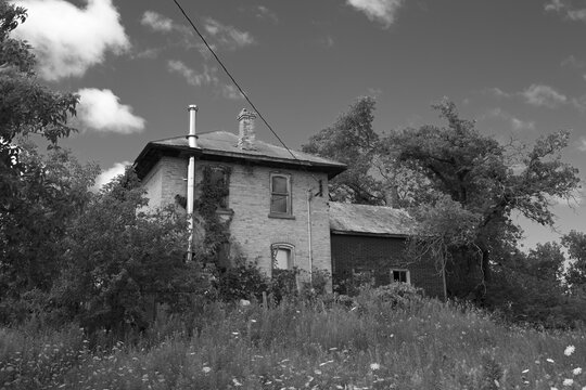 Black and white image of an Abandoned boarded up farm house 