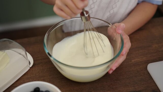 Mother and daughter whisking cream together in cozy kitchen hands focus