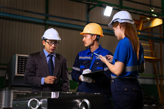 Asian factory manager and engineer team inspecting machine components with digital tablet in plant	