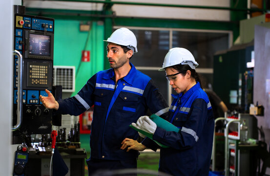 Industrial engineers inspecting cnc machine operation with clipboard in modern factory. ideal for manufacturing, automation, and industry 4.0 marketing campaigns.