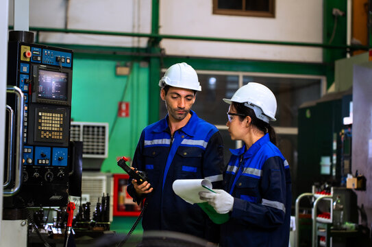 Factory workers reviewing clipboard checklist near industrial machinery in manufacturing plant. ideal for industrial quality control, team engineering, and manufacturing concepts.