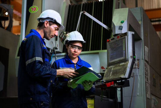 Industrial engineers inspecting cnc machine operation with clipboard in modern factory. ideal for manufacturing, automation, and industry 4.0 marketing campaigns.