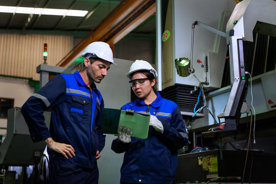 Industrial engineers inspecting cnc machine operation with clipboard in modern factory. ideal for manufacturing, automation, and industry 4.0 marketing campaigns.