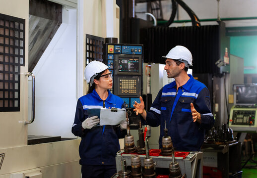 Industrial engineers inspecting cnc machine operation with clipboard in modern factory. ideal for manufacturing, automation, and industry 4.0 marketing campaigns.
