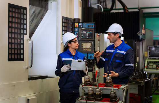 Industrial engineers inspecting cnc machine operation with clipboard in modern factory. ideal for manufacturing, automation, and industry 4.0 marketing campaigns.
