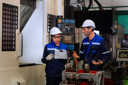 Industrial engineers inspecting cnc machine operation with clipboard in modern factory. ideal for manufacturing, automation, and industry 4.0 marketing campaigns.