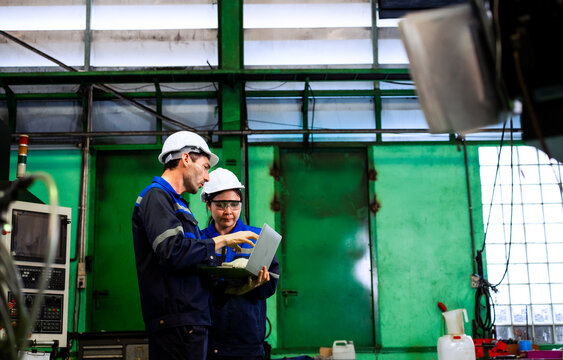 Engineers using laptop for machinery diagnostics and maintenance check in industrial plant	