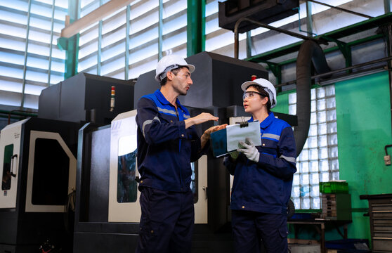 Industrial engineers inspecting cnc machine operation with clipboard in modern factory. ideal for manufacturing, automation, and industry 4.0 marketing campaigns.