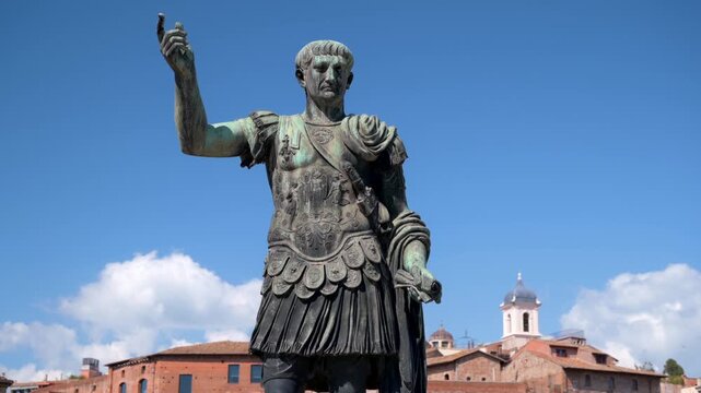 Bronze statue of emperor Trajan in Rome under blue sky with clouds in slow pan motion.