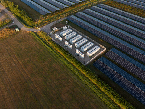 Aerial view of a large solar farm featuring rows of photovoltaic panels and a central battery energy storage system facility in the Netherlands.