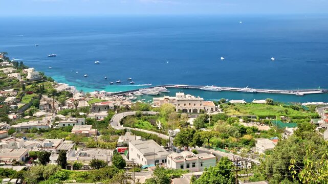 Aerial view of picturesque capri island harbor with luxury yachts and ferries docked on bright sunny day.