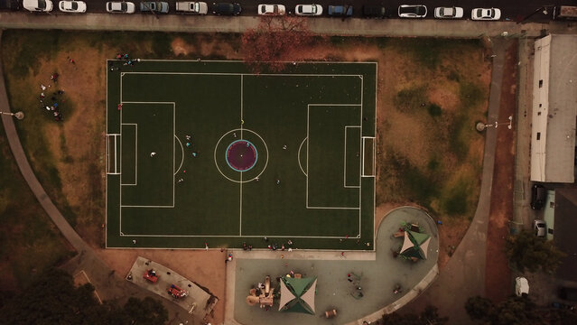 Aerial view of a soccer field with players on the pitch, surrounded by a playground and park area in Los Angeles, California, United States.