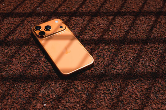 KYIV, UKRAINE - July 10, 2026 : Apple iPhone 17 Pro in Cosmic Orange color on red sport field with artificial rubber surface.