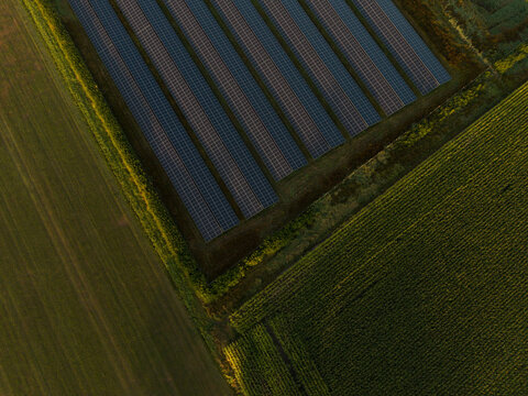 Aerial view of a solar farm with rows of photovoltaic panels installed in a rural landscape in the Netherlands.