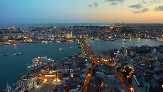 Aerial view of Galata bridge and Golden Horn in Istanbul during sunset with city lights glowing.