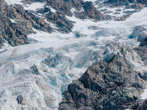 Aerial view of the Shkhara Glacier featuring massive ice formations, deep crevasses, and rugged rocky mountain slopes in Ushguli, Samegrelo-Zemo Svanet, Georgia.