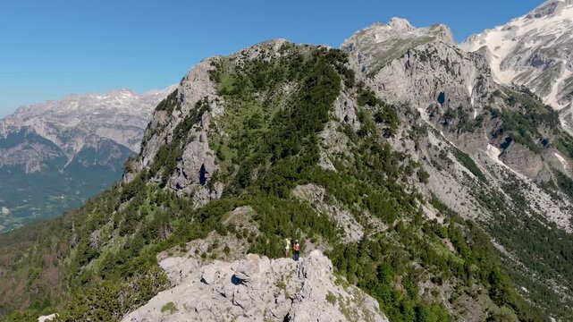 Albania offers an unforgettable experience at Valbona Pass, where majestic mountains meet serene trails. Discover lush greenery and panoramic views, A couple walking in the Albanian Alps near Theth
