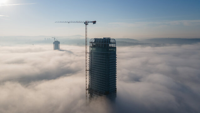 Aerial view of Kula Beograd Waterfront under construction rising above a thick layer of morning fog with a tall crane visible against the clear sky in Belgrade, City of Belgrade, Serbia.